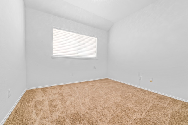 empty room with vaulted ceiling and light colored carpet