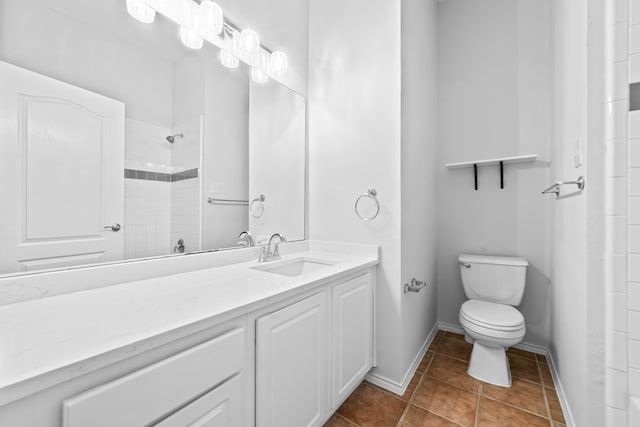 bathroom featuring tile patterned floors, a tile shower, vanity, and toilet