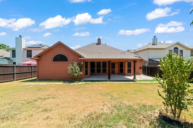 back of house with solar panels, a patio area, and a yard