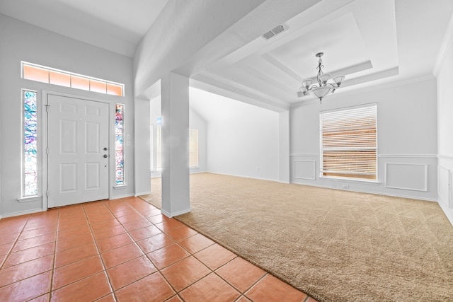 tiled foyer featuring a tray ceiling and a chandelier