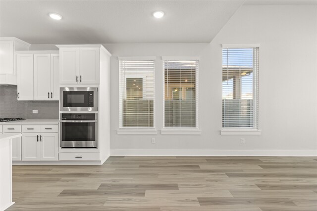 kitchen with oven, decorative backsplash, white cabinets, and gas cooktop