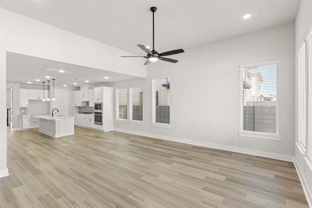 unfurnished living room featuring sink, light hardwood / wood-style floors, and ceiling fan