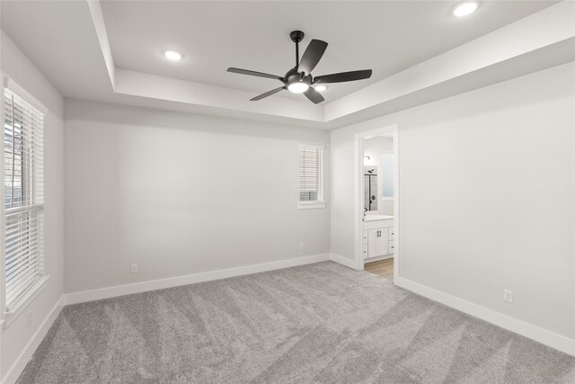 interior space featuring light colored carpet, a tray ceiling, and ceiling fan