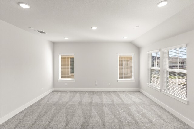 spare room featuring lofted ceiling and light colored carpet