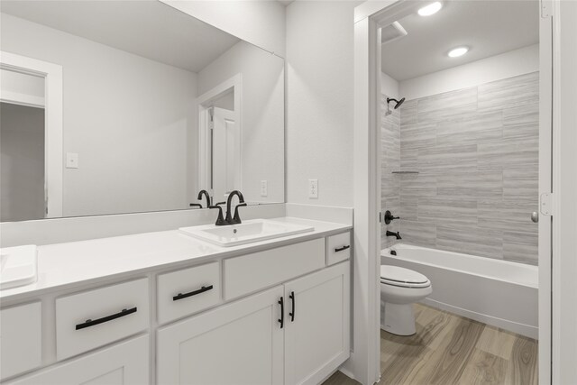 full bathroom featuring vanity, toilet, hardwood / wood-style flooring, and tiled shower / bath