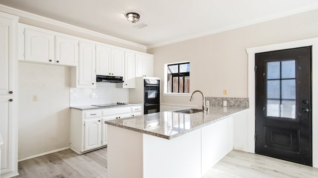 kitchen featuring sink, black appliances, light stone counters, kitchen peninsula, and white cabinets