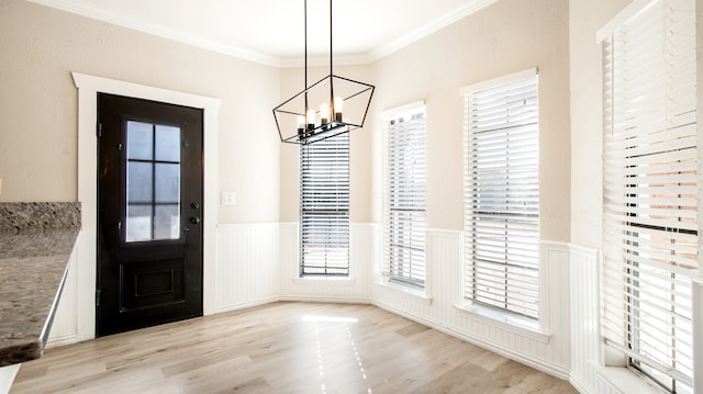 entrance foyer featuring light hardwood / wood-style floors, a chandelier, and crown molding