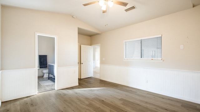 unfurnished bedroom with ceiling fan, vaulted ceiling, light hardwood / wood-style floors, and ensuite bath