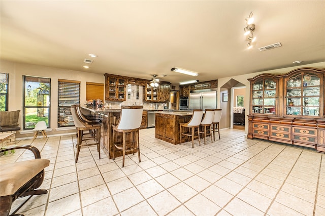 kitchen featuring ceiling fan, track lighting, appliances with stainless steel finishes, light tile patterned floors, and kitchen peninsula