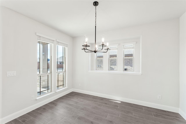 unfurnished dining area with dark wood-type flooring and a notable chandelier