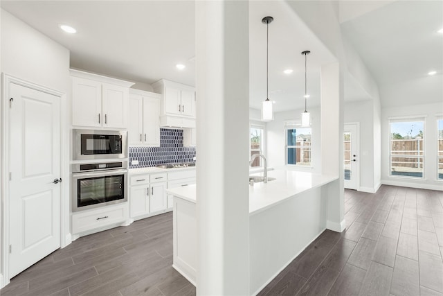 kitchen with black microwave, oven, white cabinetry, and decorative light fixtures