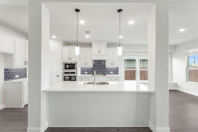 kitchen featuring sink, white cabinetry, built in microwave, decorative light fixtures, and stainless steel oven