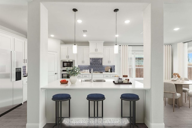 kitchen with a kitchen breakfast bar, black microwave, high quality fridge, and pendant lighting