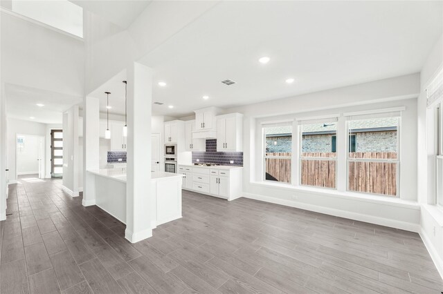 kitchen featuring black microwave, decorative light fixtures, decorative backsplash, hardwood / wood-style floors, and white cabinetry