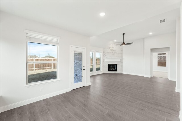 unfurnished living room with wood-type flooring, plenty of natural light, and a premium fireplace