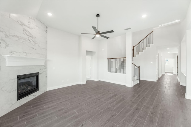 unfurnished living room with ceiling fan, vaulted ceiling, a high end fireplace, and dark wood-type flooring