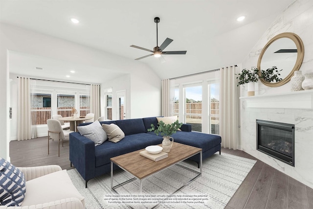 living room featuring hardwood / wood-style floors, vaulted ceiling, ceiling fan, and a fireplace