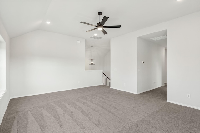 empty room with lofted ceiling, dark colored carpet, and ceiling fan with notable chandelier