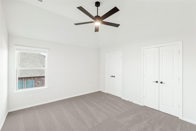 unfurnished bedroom with light carpet, vaulted ceiling, two closets, and ceiling fan