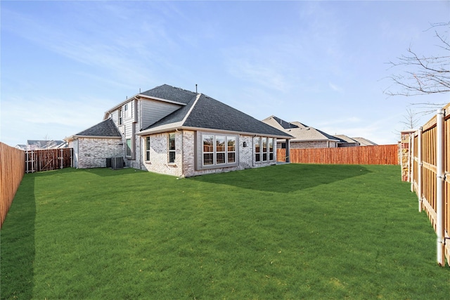 back of property featuring central air condition unit and a lawn