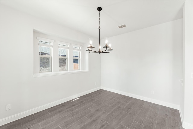 empty room featuring a chandelier and wood-type flooring