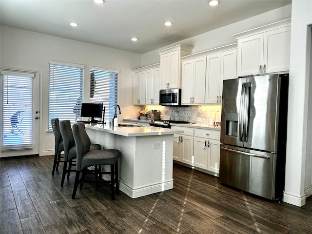 kitchen with white cabinetry, sink, tasteful backsplash, dark hardwood / wood-style flooring, and appliances with stainless steel finishes