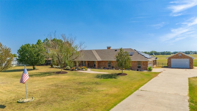 single story home featuring brick siding, a detached garage, solar panels, and a front yard