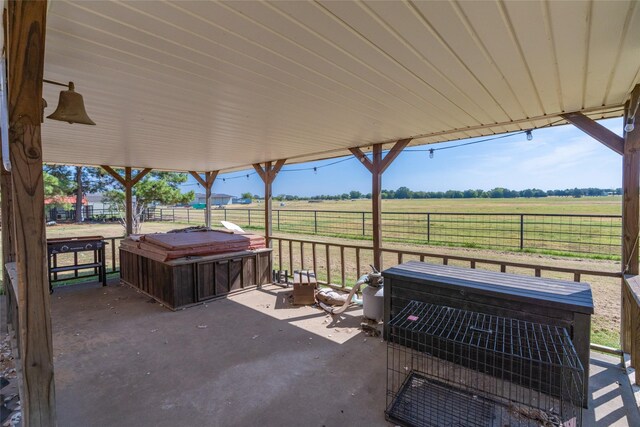 view of patio / terrace featuring a hot tub and a rural view