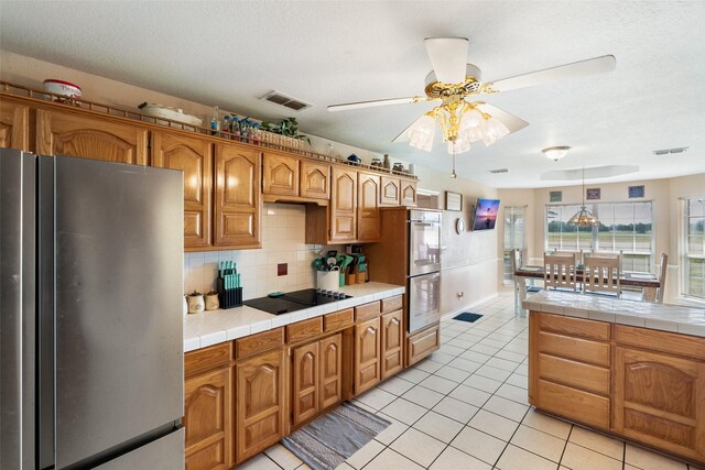 kitchen with a textured ceiling, tile counters, stainless steel refrigerator, white dishwasher, and sink