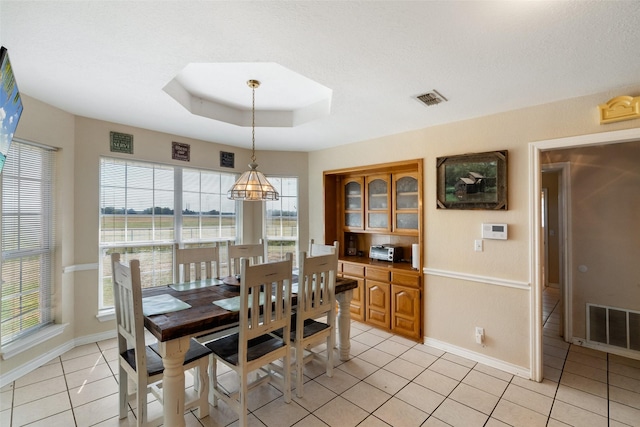 tiled dining area featuring a wealth of natural light and a raised ceiling