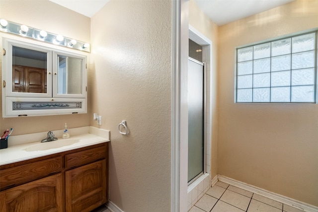 bathroom with vanity, baseboards, tile patterned flooring, and a shower stall