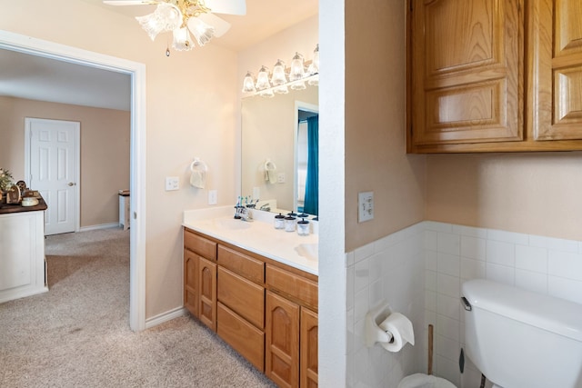 full bathroom featuring double vanity, a ceiling fan, toilet, a sink, and carpet floors