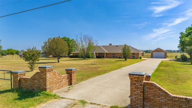 view of front of house with a detached garage, concrete driveway, an outdoor structure, fence, and a front yard