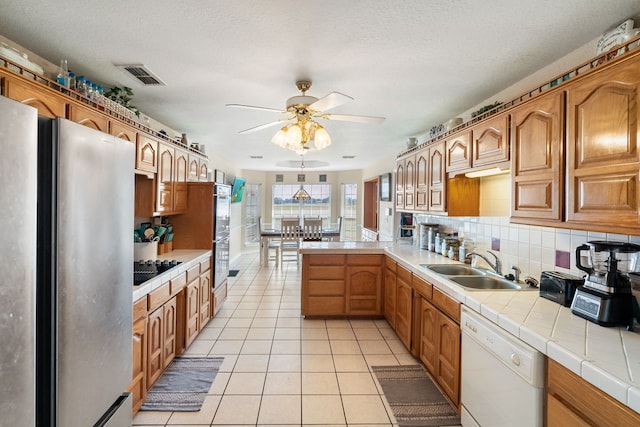 kitchen with a sink, visible vents, ceiling fan, tile countertops, and appliances with stainless steel finishes