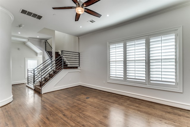 spare room featuring crown molding, ceiling fan, dark wood-type flooring, and a wealth of natural light