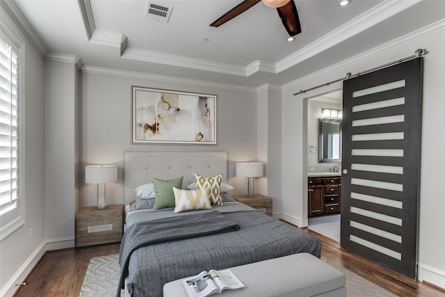 bedroom featuring connected bathroom, dark wood-type flooring, crown molding, and ceiling fan