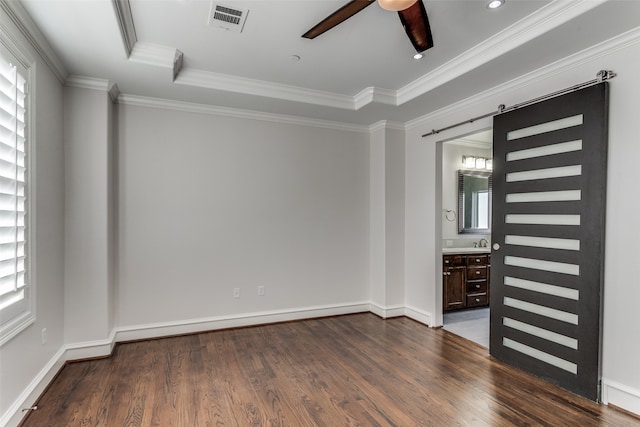 unfurnished room with crown molding, dark hardwood / wood-style floors, a barn door, and a tray ceiling