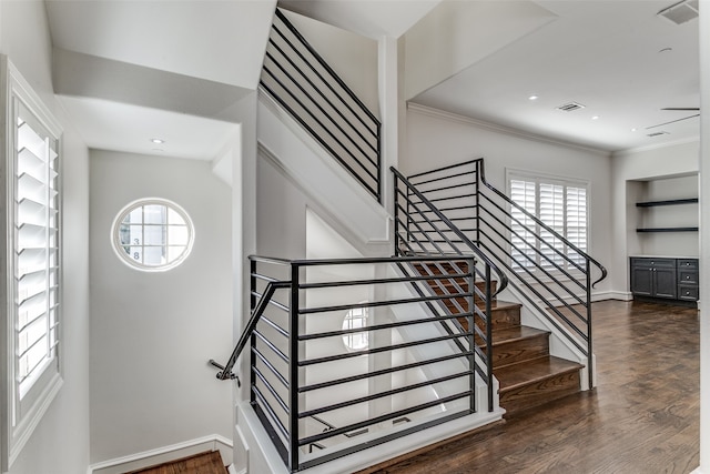 stairway with ornamental molding, wood-type flooring, and a wealth of natural light