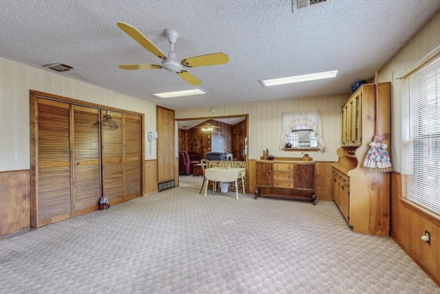 kitchen featuring wood walls, visible vents, brown cabinets, and light colored carpet