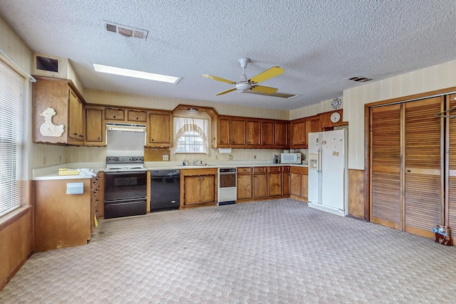 kitchen with brown cabinets, black appliances, visible vents, and light countertops