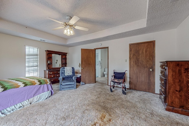 bedroom with a raised ceiling, light carpet, a textured ceiling, and ensuite bathroom