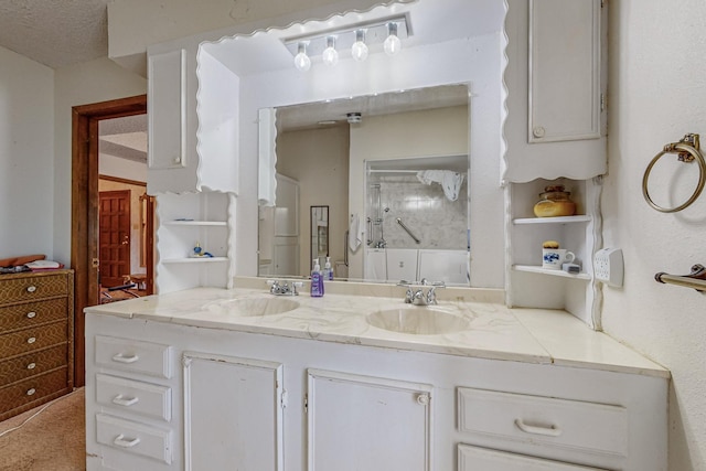 bathroom with a shower, a sink, a textured ceiling, and double vanity