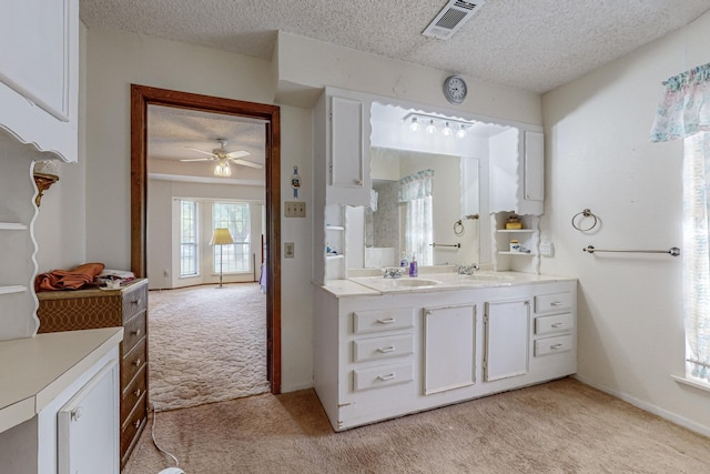 bathroom with a textured ceiling, a sink, visible vents, a ceiling fan, and double vanity