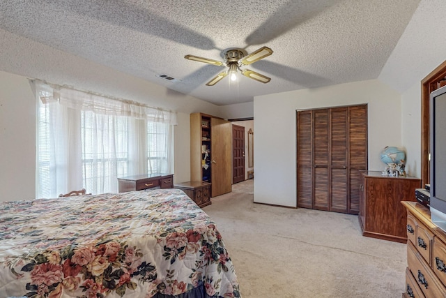 bedroom with a closet, visible vents, a ceiling fan, light carpet, and a textured ceiling