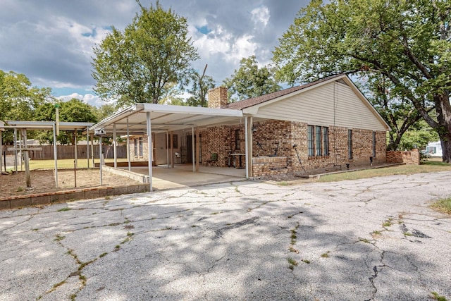 exterior space with brick siding, a chimney, and aphalt driveway