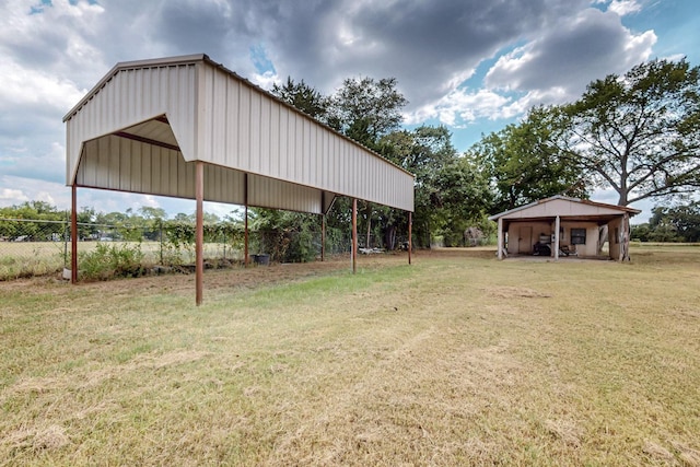 view of yard featuring a carport, an outbuilding, and fence