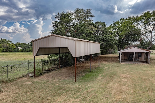 view of yard with fence, a carport, and an outbuilding