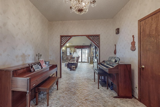 corridor with a notable chandelier, arched walkways, a textured ceiling, and light colored carpet