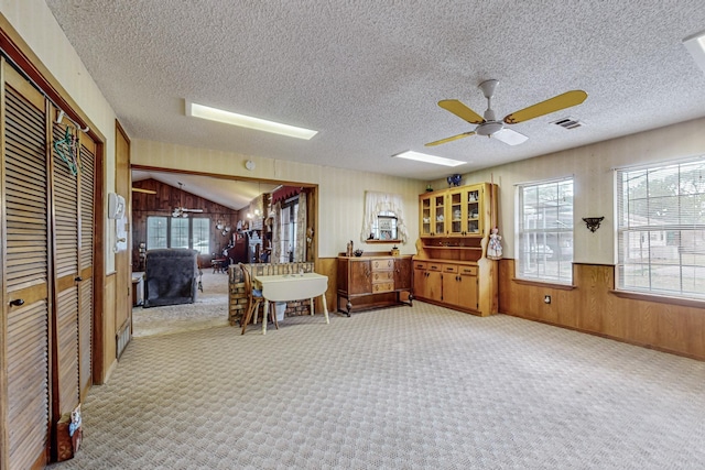 interior space featuring wood walls, plenty of natural light, visible vents, and light colored carpet