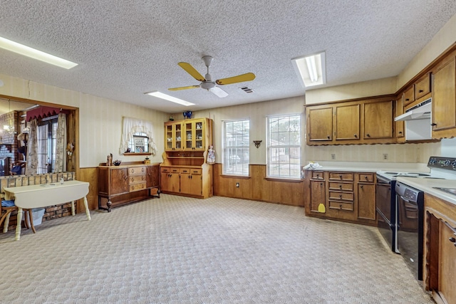 kitchen with under cabinet range hood, light countertops, dishwasher, and brown cabinetry